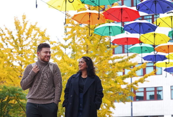 Two students walking and smiling on University Square