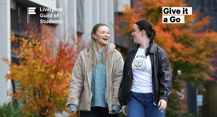 Two females walking outside smiling at one another